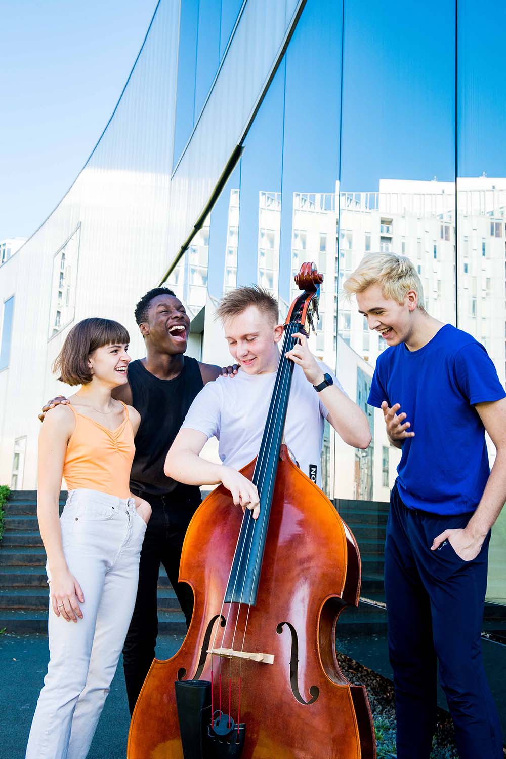 Four students gathering around a double bass whilst one student plays