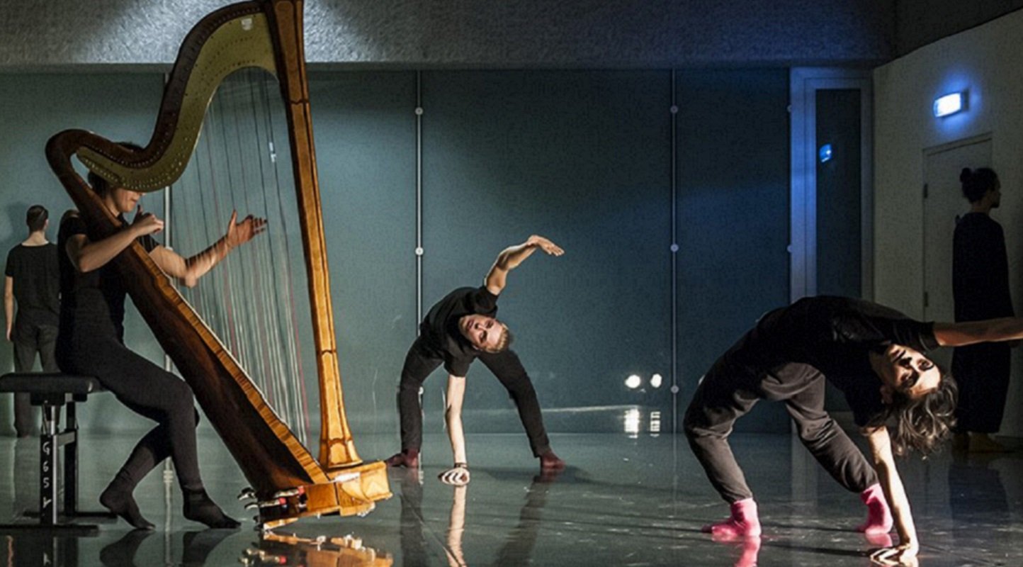 A musician plays the harb whilst two dancers bend backwards