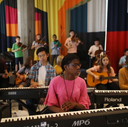 A group of young musicians playing keyboard and strings