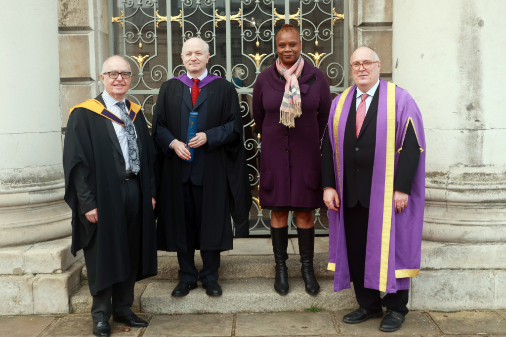 Alan Davey, Sir George Benjamin, Wozzy Brewster and Havilland Willshire, standing on steps outside King Charles Court in graduation robes