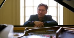 Douglas finch sat at open lid grand piano