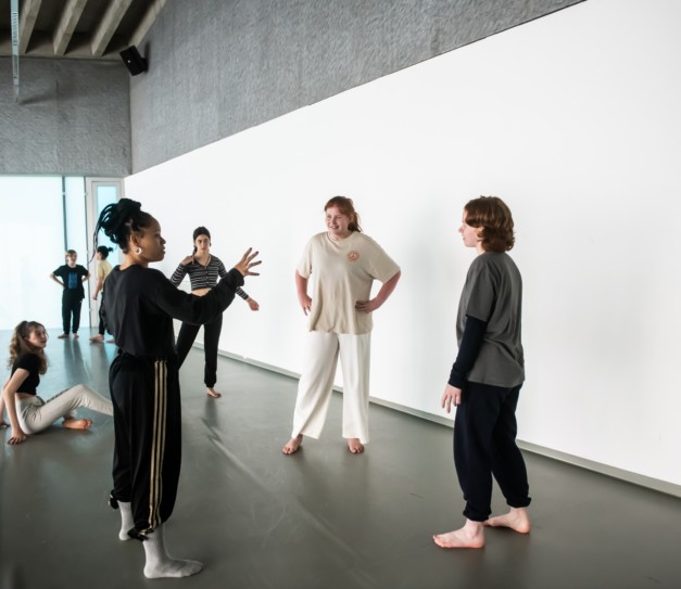 Choreographer Sarah Golding talking to two dancers in rehearsal studio