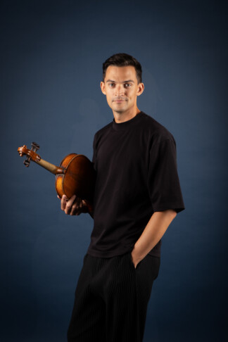 A photo of Stephen Upshaw, a white man, dressed in black and holding a violin