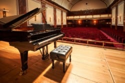 Open lid grand piano on stage in front of empty Wigmore Hall auditorium