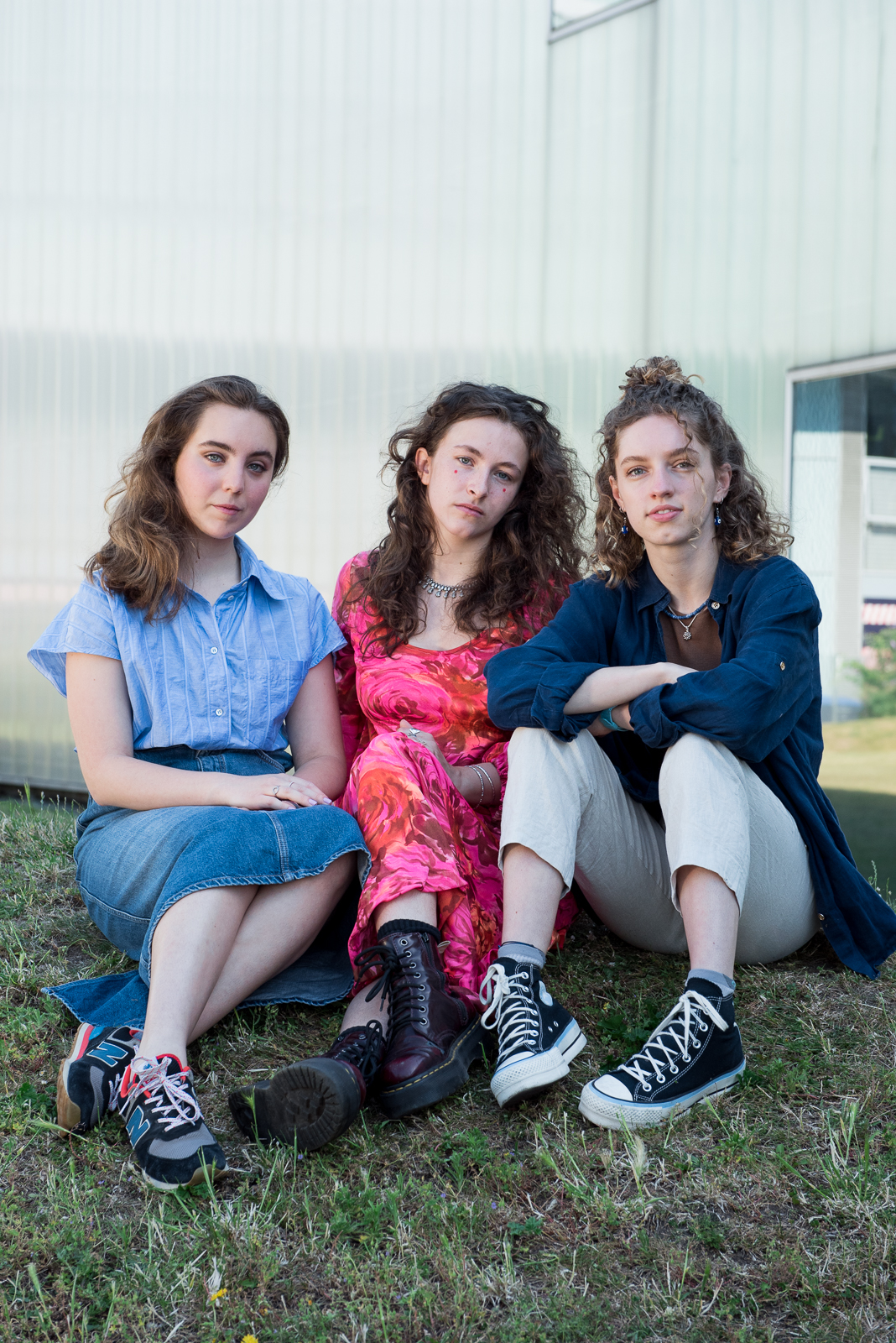 Ruby De Ville Morel, Mila Fernandez and Melissa Heywood sitting together in a row on a grassy bank.