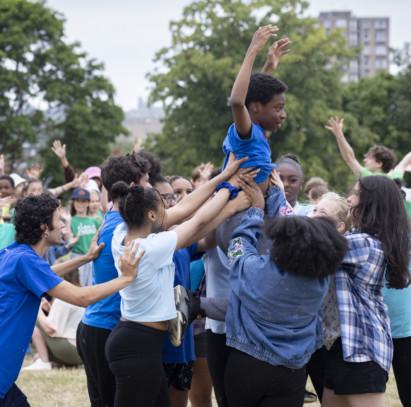 Group of young performers in a Mountsfield Park, holding up a male performer