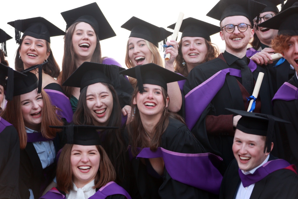 Students smiling and laughing wearing graduation caps and gowns