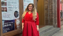 Valerija stands in front of Carnegie Hall, before her performance as Laureate Gala winner. She has long blonde hair and wears a red dress.
