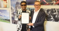 A.R. Rahman stands next to TL Principal Anthony Bowne. They are jointly holding a signed agreement between TL and KM Music Conservatory.